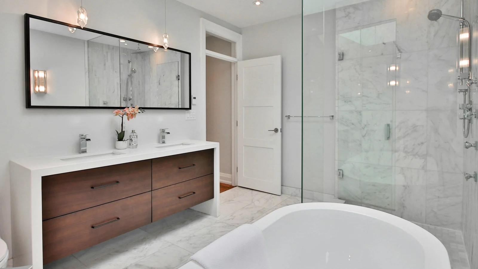 Baño luminoso con mampara de vidrio y espejo grande sobre el lavabo